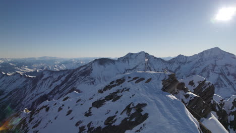 Toma-Aérea-En-La-Cordillera-En-Un-Día-Soleado-En-El-Pico-Más-Alto-De-Kitzsteinhorn-En-Austria-Con-Una-Gran-Cruz-En-él