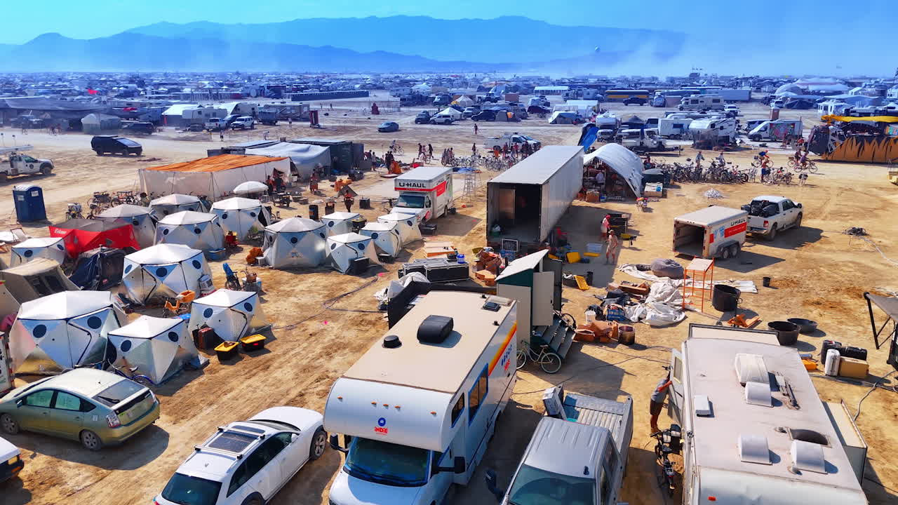 Festival camp of tents and vehicles. Tents, RVs and supply trucks fill the busy desert camp where participants prepare their gear