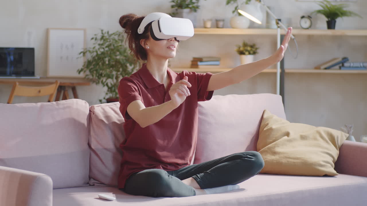 mujer usando gafas vr mientras está sentada en el sofá en casa