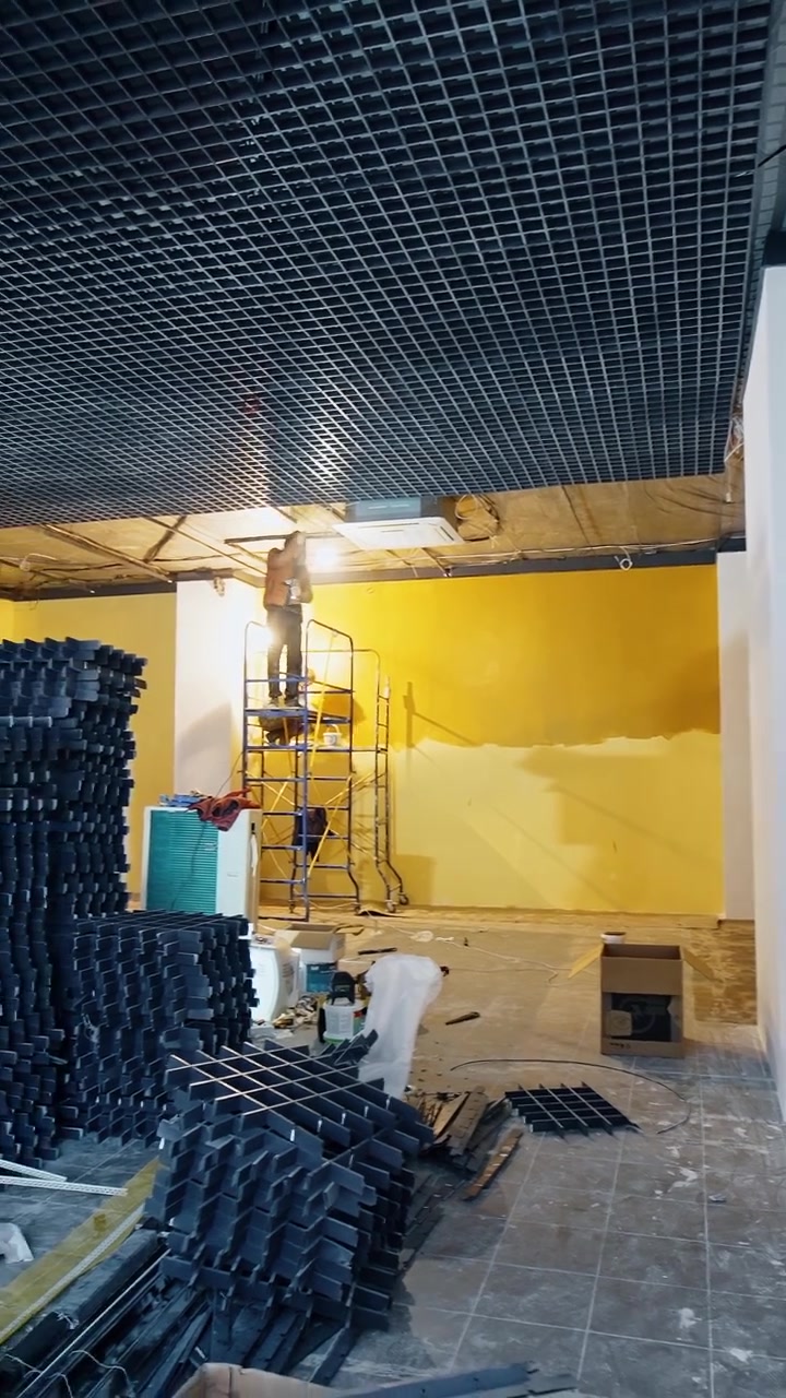 Unos hombres instalan el equipo y la decoración en el techo de la gran sala. Los constructores están de pie en las torres de andamios trabajando. Video vertical.