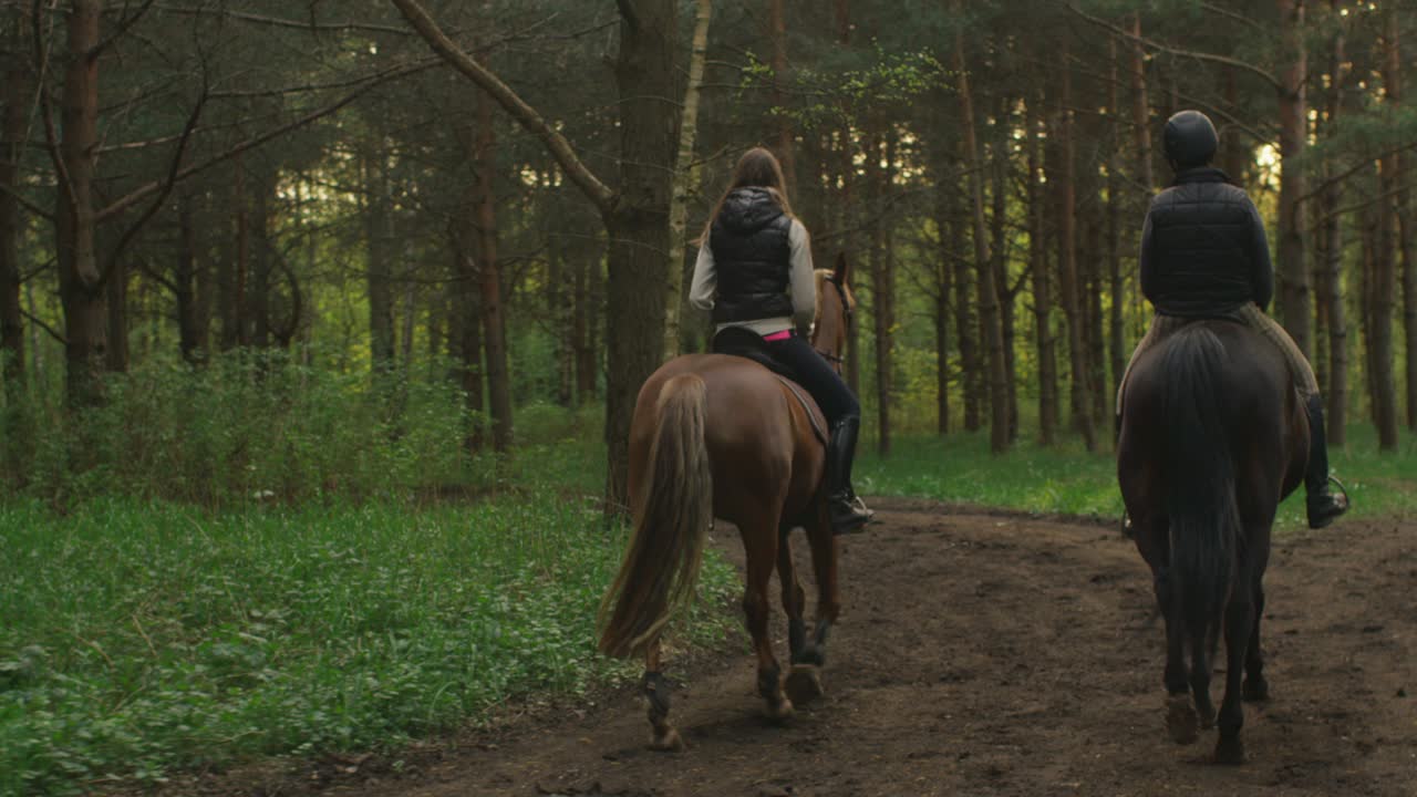 dos chicas jóvenes montando caballos en el bosque