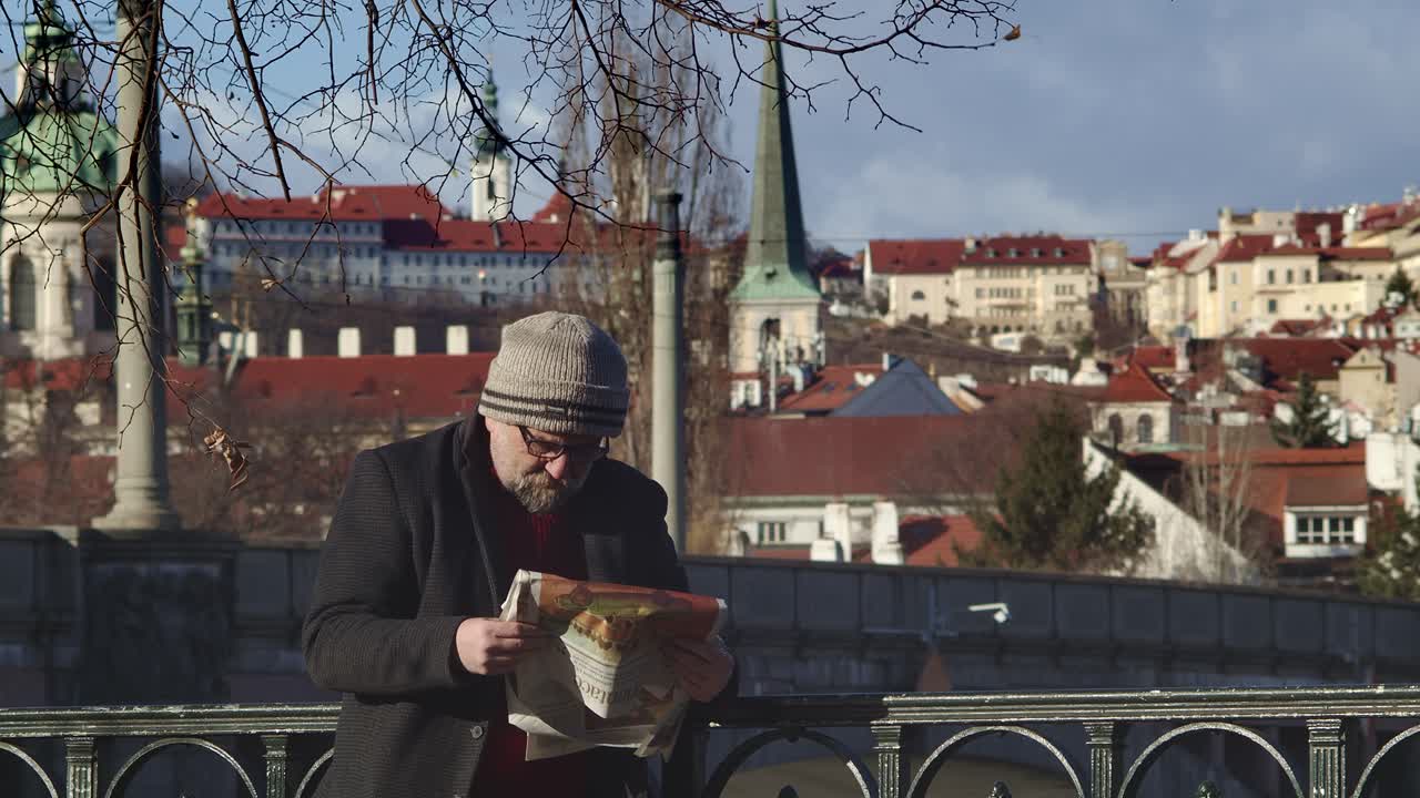 un anciano lee un periódico en el terraplén vltava