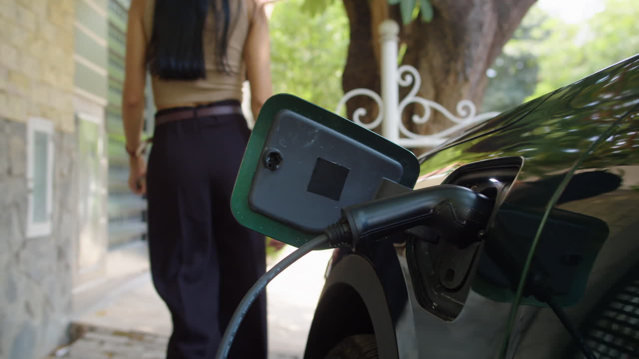 женщина заряжает электрический автомобиль дома