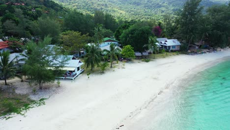 beach cabins on shore of tropical island with lush vegetation, palm trees and white sandy beach washed by turquoise lagoon in , turks and caicos