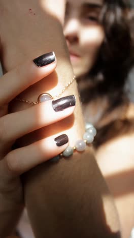 woman's wrist with bracelet and black nails