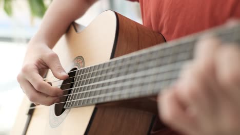 teacher instructing teenage boy playing guitar, music lesson at home.