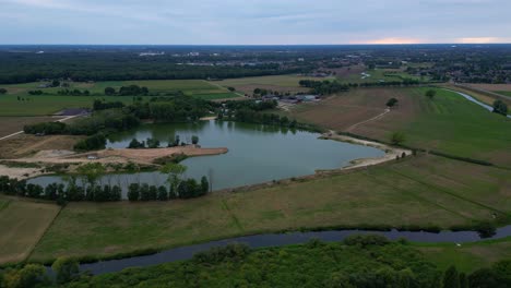 aerial flying towards lake surrounded by rural fields in the netherlands