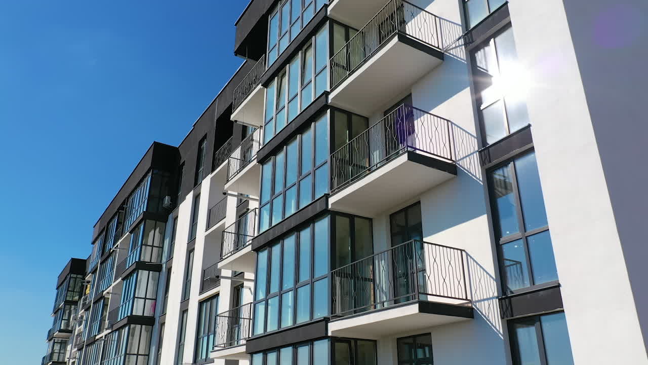 Beautiful design of multistorey building. New apartment with balconies against blue sky. Exterior of residential building.