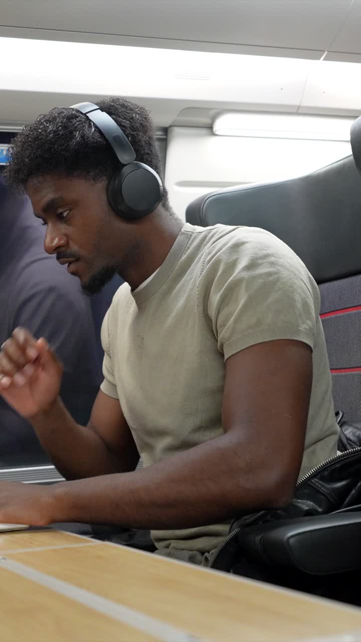 Man Working on Laptop with Headphones on Train