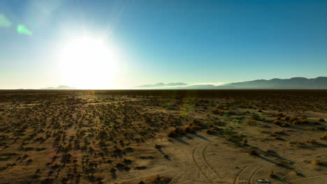 The-sun-shines-brightly-over-the-horizon-of-the-vast-Mojave-Desert-landscape---sliding-aerial-view