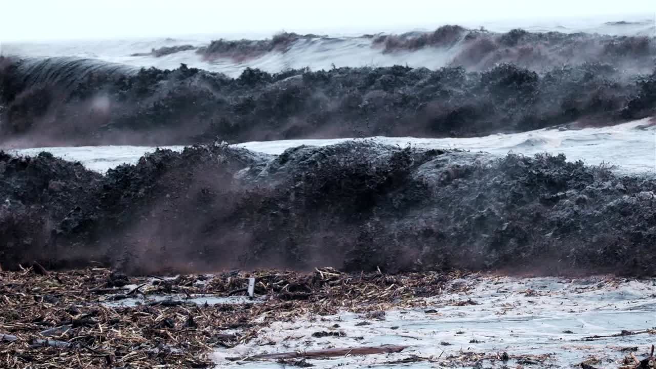 잔해로 가득 찬 어두운 파도가 충돌합니다.
