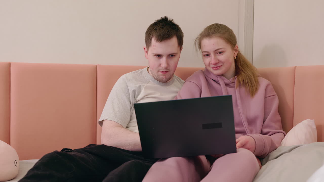 una pareja viendo algo en línea en una computadora portátil