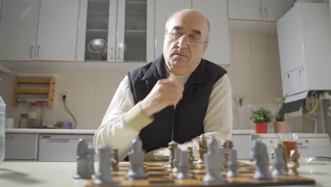 Thoughtful old man playing chess by himself.