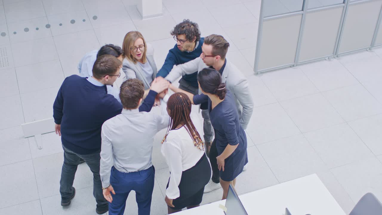 trabajadores de oficina haciendo ejercicio de team building apilando las manos juntos en el espíritu unificador de la creatividad y la causa común. ocho personas exitosas aplaudiendo juntos. fotografía de ángulo alto en una oficina moderna