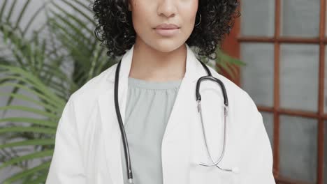 Portrait-of-biracial-female-doctor-wearing-lab-coat,-using-tablet,-slow-motion