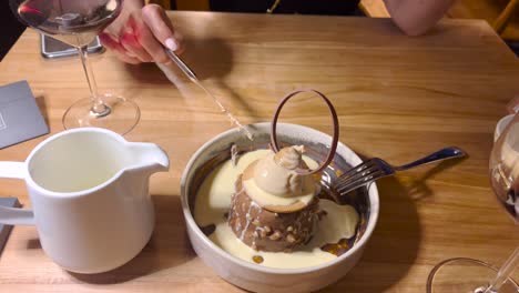 woman-eats-an-Petite-gateau-with-hot-chocolate-sauce-poured-over,-very-gourmet-and-famous-in-Lisbon