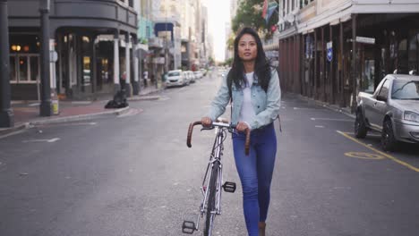 Mujer-De-Raza-Mixta-Caminando-Junto-A-Su-Bicicleta-En-La-Calle