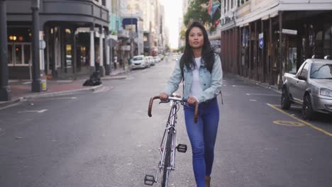 mixed race woman walking next to her bike on the street