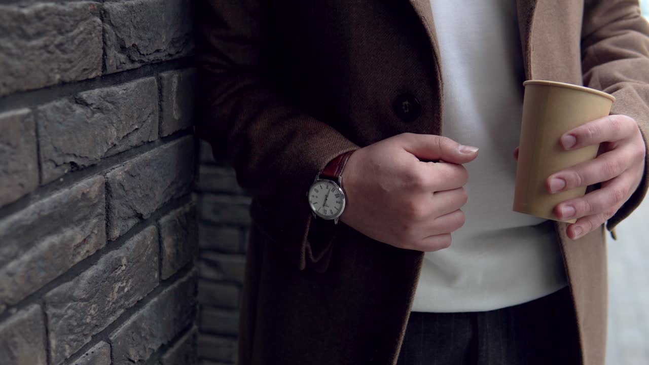 Handsome businessman in brown coat with coffee near the office. Close-up