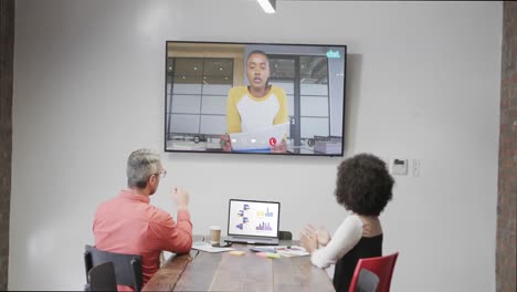 Diverse-business-people-on-video-call-with-african-american-male-colleaguge-on-tv-screen