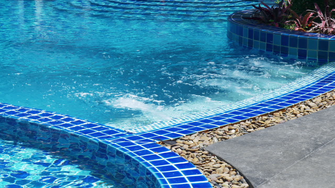 En swimmingpool med blå fliser og vand, der sprøjter ud fra siden og skaber bobler i jacuzzistil