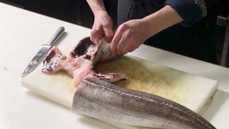 chef cleaning hake's head over a kitchen counter at spanish restaurant