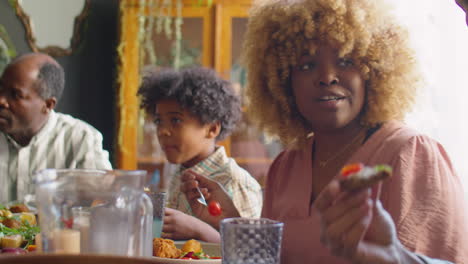 african american woman chatting with son at family dinner