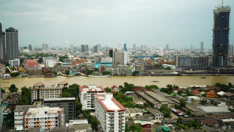 Lapso-De-Tiempo-Del-Río-Chao-Phraya-De-La-Ciudad-De-Bangkok,-Lapso-De-Tiempo-Del-Río-Fangoso-Con-El-Fondo-Del-Horizonte-De-La-Ciudad-Durante-La-Temporada-De-Lluvias