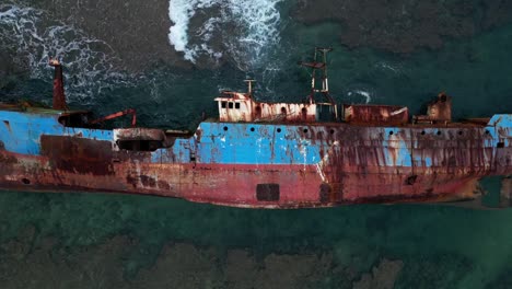 sunken rusty ship lying on side among crashing waves