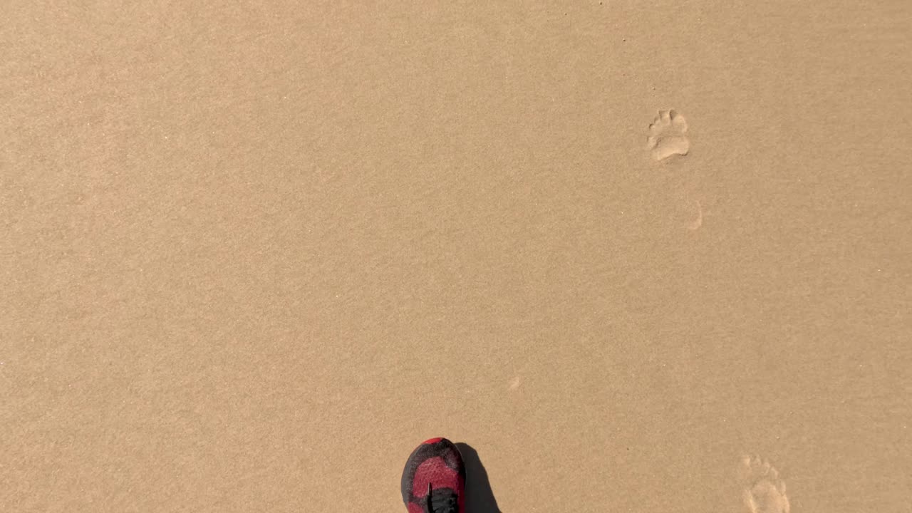 Impronte su una spiaggia sabbiosa con scarpe rosse