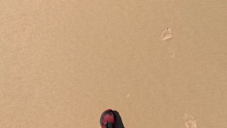 footsteps on sandy beach with red shoes