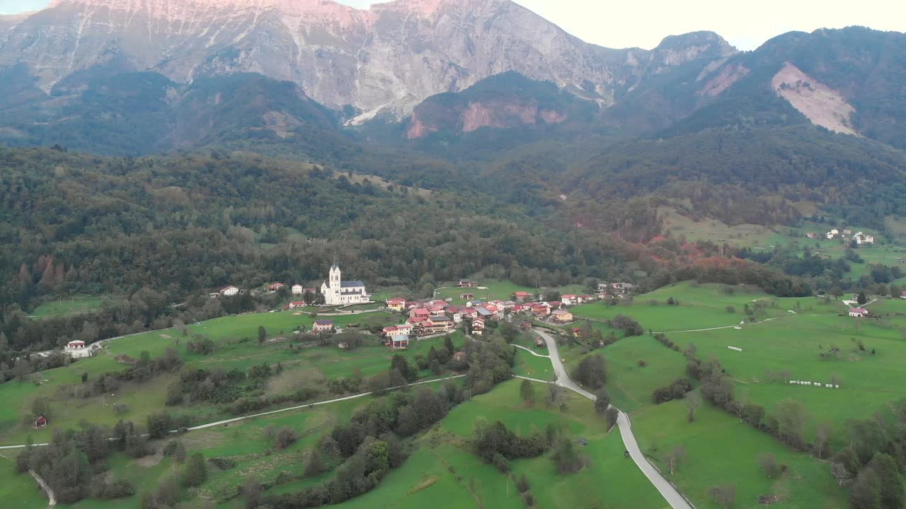 circular aerial shot of Dreznica village below majestic mountains, early autumn evening
