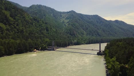 un avión volando verticalmente hacia arriba sobre un río de montaña un puente de automóviles personas que pasan a través de él