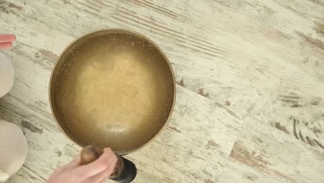 Crop-sound-therapist-playing-bowl-gong-with-rippled-aqua