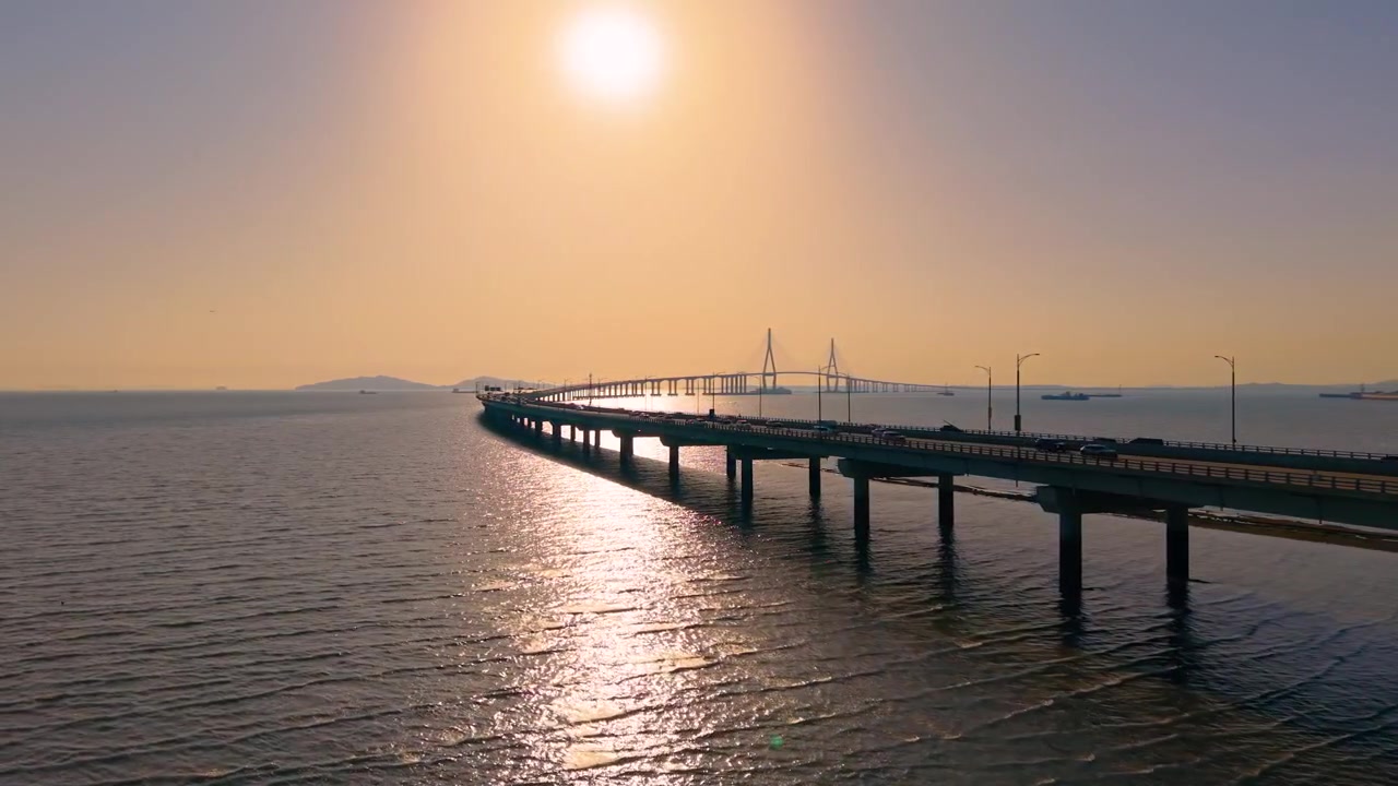 Il Ponte di Incheon si estende sul mare calmo mentre il traffico scorre sotto il sole splendente del tramonto che si riflette sull'acqua in Corea del Sud - ripresa aerea in parallasse