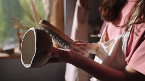 woman cleaning a pottery bowl in a workshop