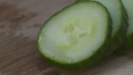 macro close-up of fresh, crisp, sliced english cucumber on a wood cutting board