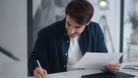 hombre sonriente haciendo notas en el diagrama financiero. hombre disfrutando de los resultados del proyecto