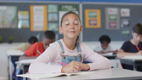 in school, girl smiling and sitting at desk with open book in classroom