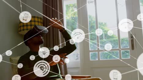 Animation-of-network-of-connections-with-icons-over-businessman-wearing-vr-headset