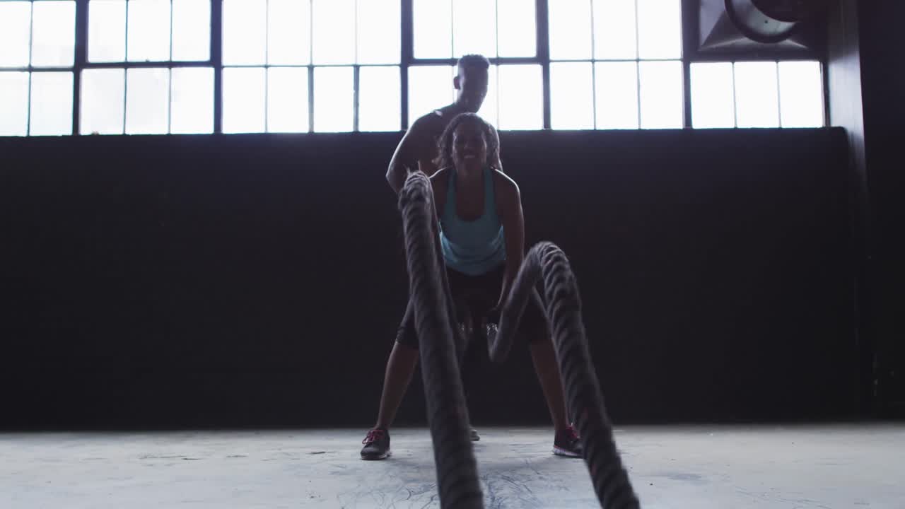 아프리카계 미국인 여성 이  ⁇  비어 있는 도시 건물 에서  ⁇ 줄 을 싸우는 운동 을 하고 있으며, 그 남자 는 그 여자 를 응원 하고 있다