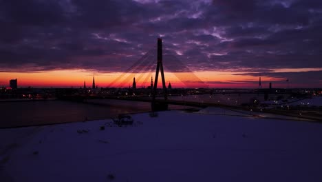 soft purple clouds roll over riga's skyline as sunrise glows behind vanšu bridge