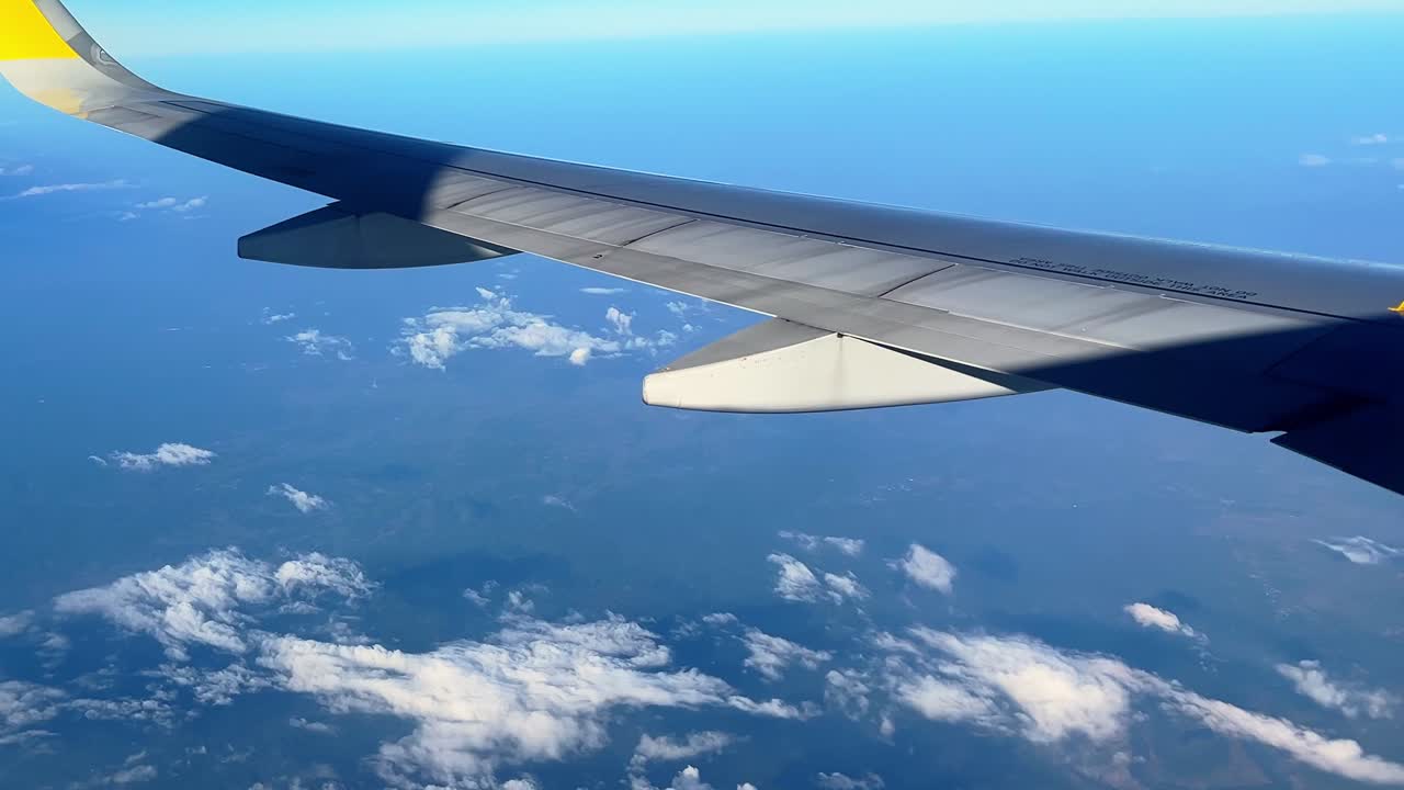 Wing view from airplane window flying above clouds—ideal for travel, aviation, freedom, business, or wanderlust themes