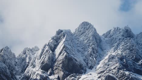 Escarpadas-Montañas-Nevadas-Con-Hermosas-Nubes-Que-Se-Acercan-Con-Un-Cielo-Azul