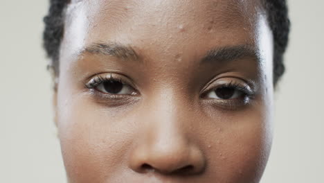 ojos de una mujer afroamericana con cabello oscuro corto en fondo beige, cámara lenta