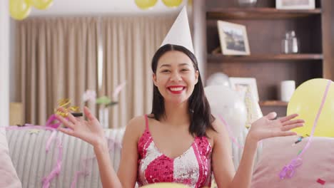 video of smiling biracial woman in party hat and dressed in pink dress