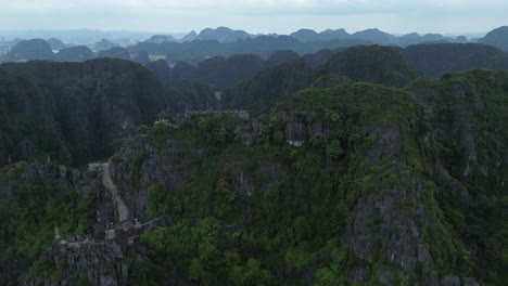 drone zoom in on dramatic karst mountain covered in dense green vegetation in ninh binh region