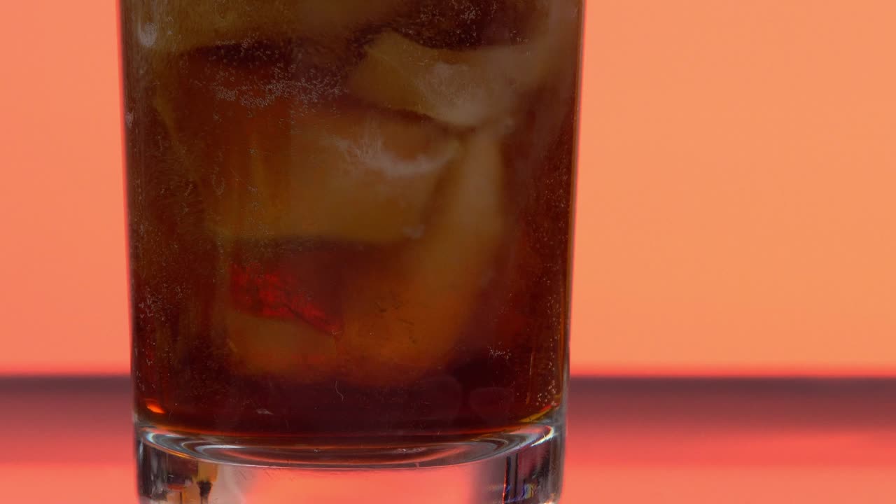 disparo estabilizado de la base de un vaso lleno de hielo mientras se está llenando con soda cola.