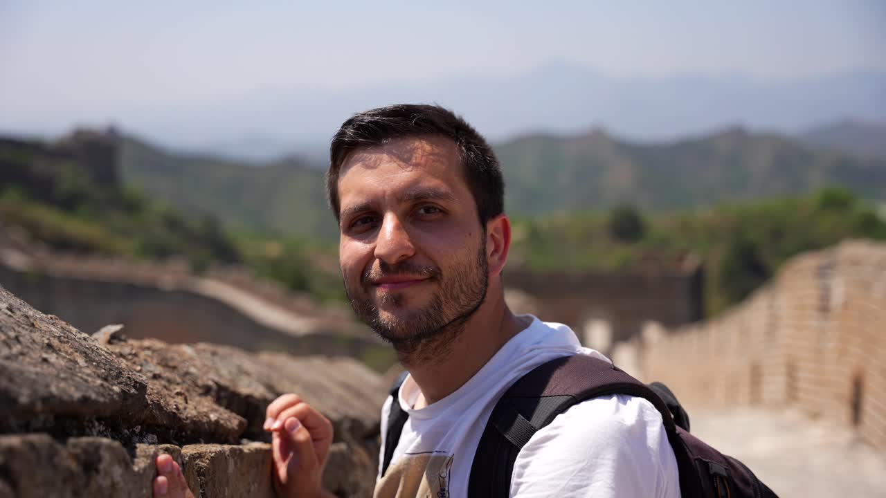 hombre español sonriendo felizmente a la cámara en la gran muralla de china
