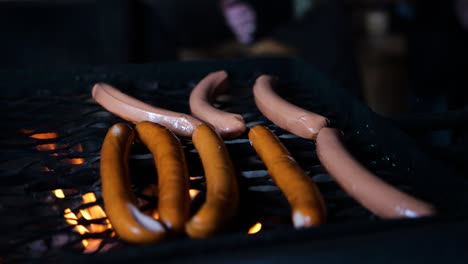 Cámara-Tirando-De-Una-Toma-De-Deliciosas-Salchichas-Frescas-En-Una-Parrilla-De-Barbacoa-Sobre-Un-Fuego